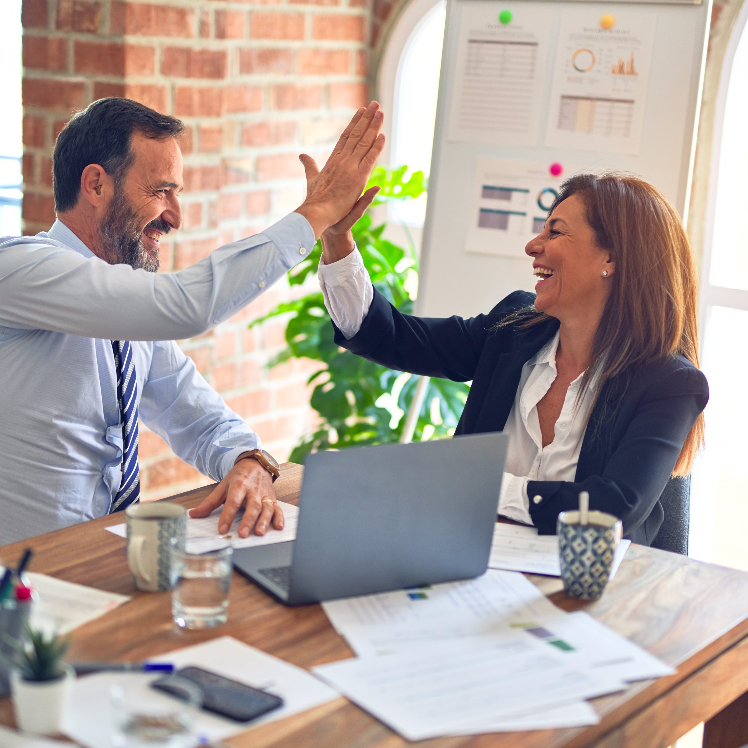 coworkers high five over laptop